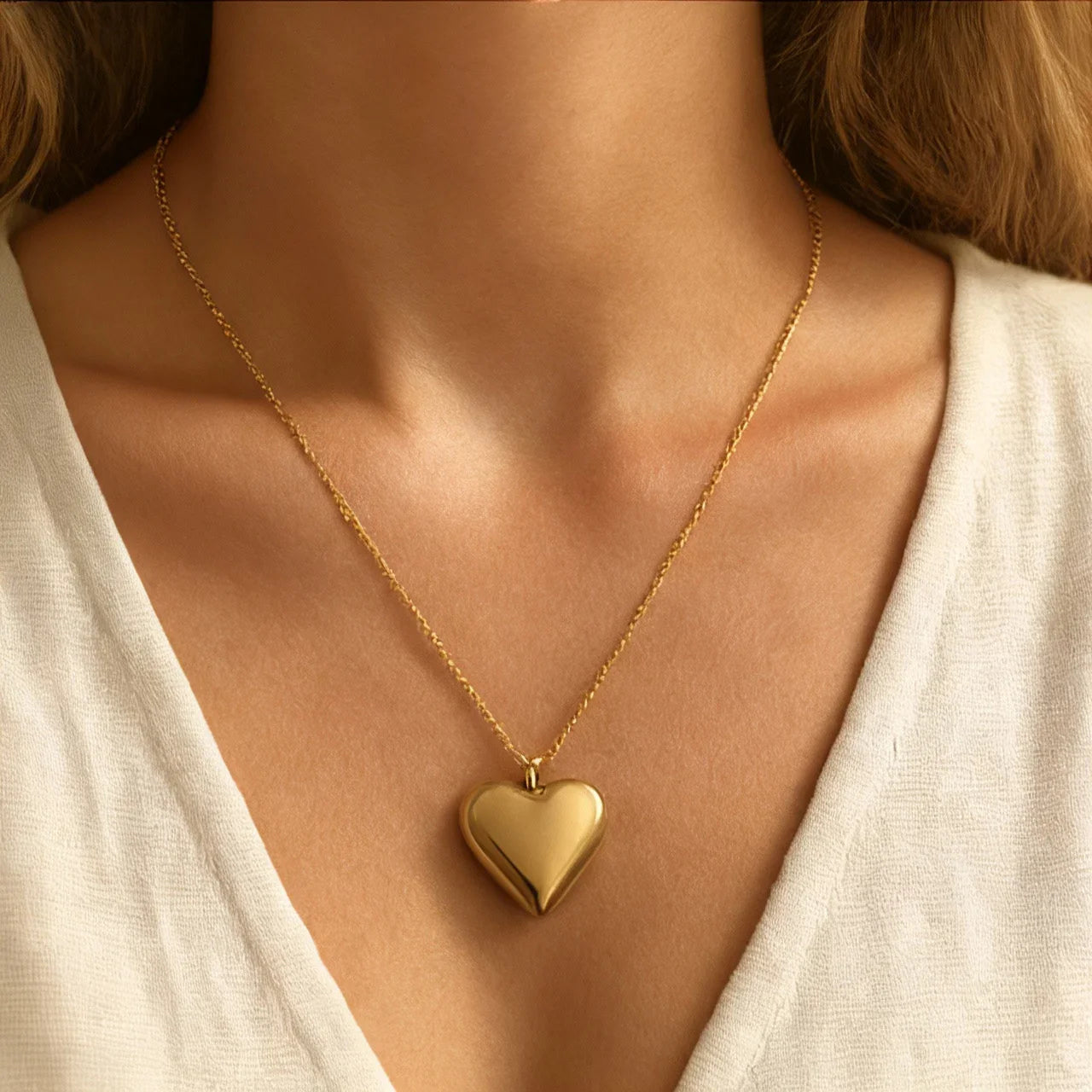 Golden heart pendant necklace on model wearing white blouse – handmade jewelry from Bali with minimalist Mediterranean charm