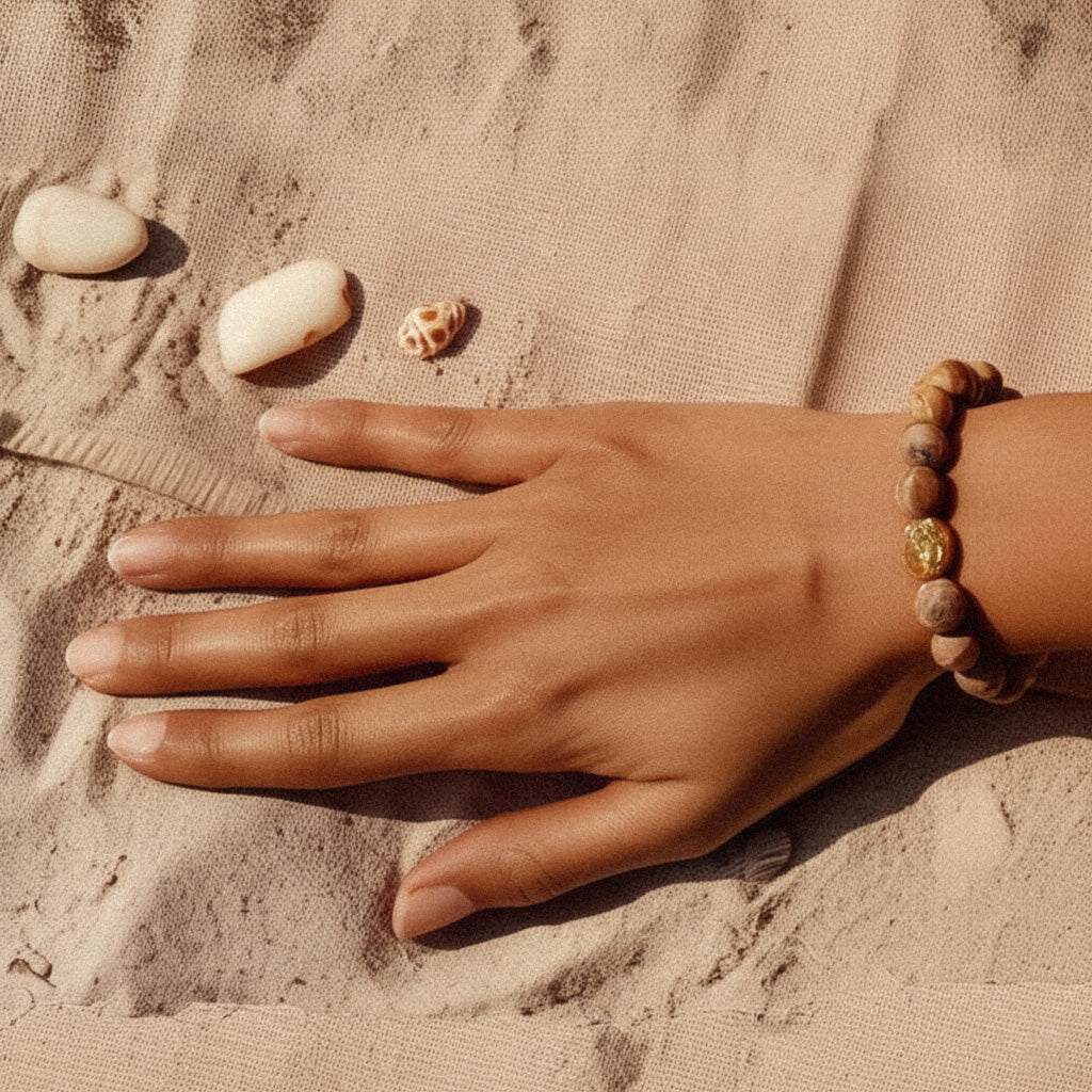 Woman wearing Earthstone Jasper beaded bracelet with golden accents in a serene outdoor setting, capturing a natural, boho-inspired lifestyle moment.