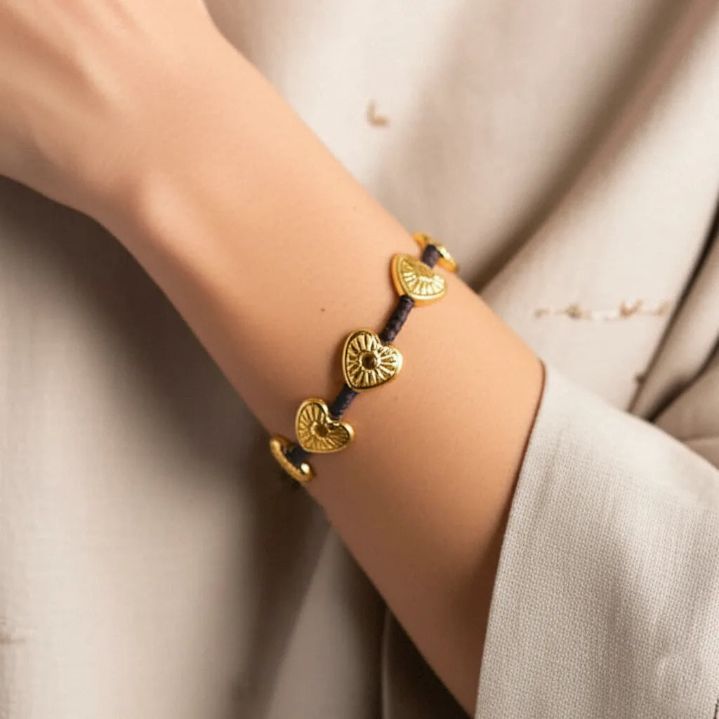 Woman wearing the Golden Blossom Hearts Bracelet featuring radiant gold-toned heart charms—styled with a soft, natural look reflecting Bali’s artisanal charm.