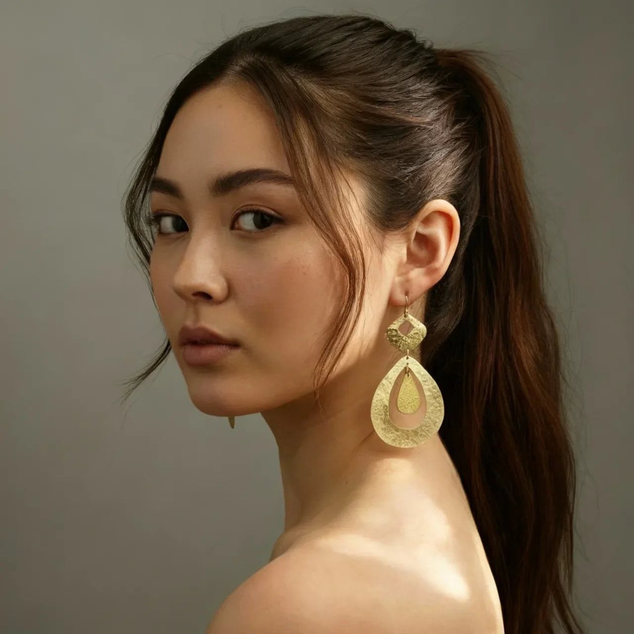 Model wearing golden drop earrings with hammered texture – artisanal handmade jewelry by Camins, Mediterranean boho chic style.