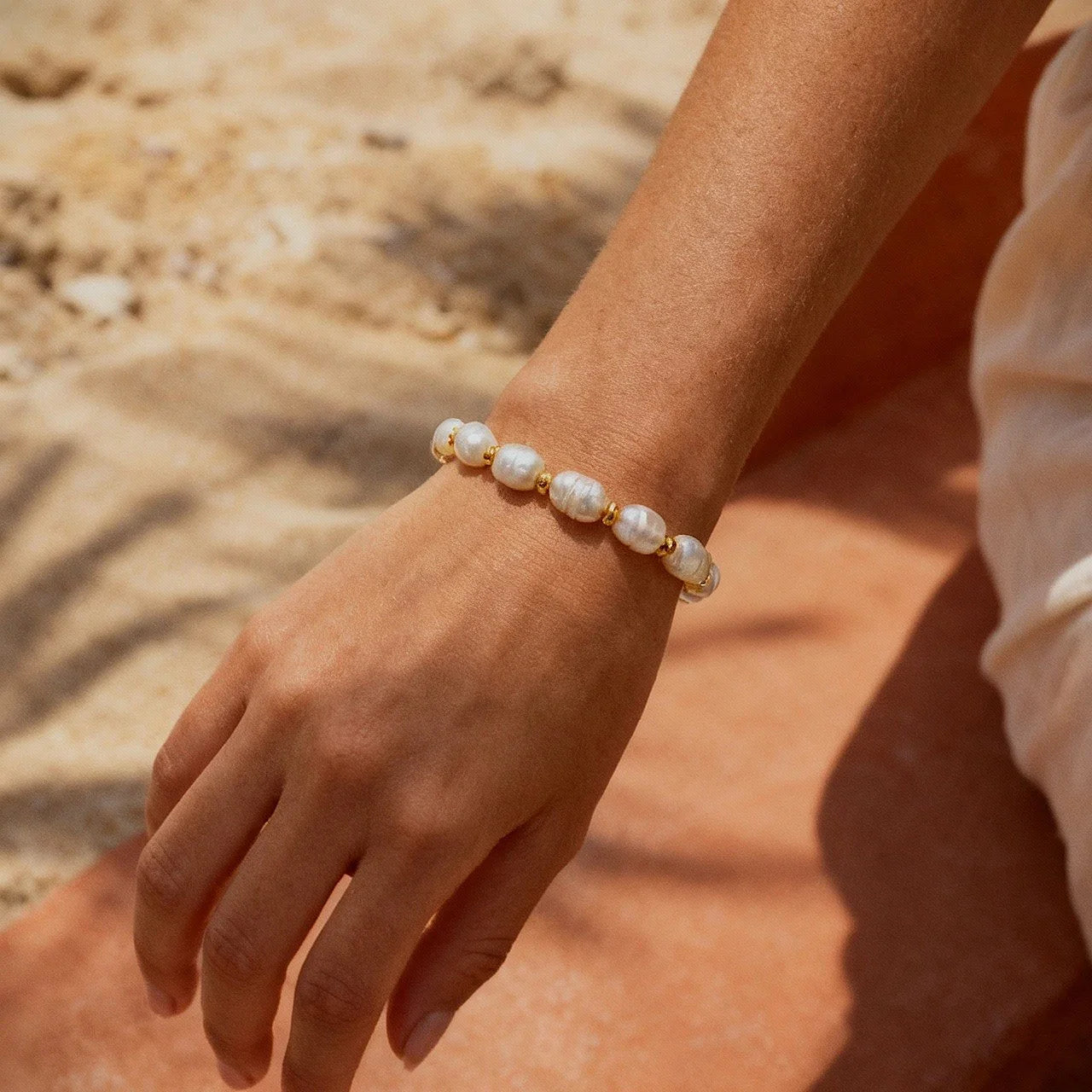 Hand wearing Golden Radiance Pearl Bracelet, handmade in Bali with natural pearls and gold accents – Camins Jewelry
