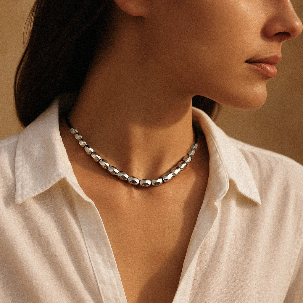Close-up of a person wearing a silver chain necklace with a neutral background