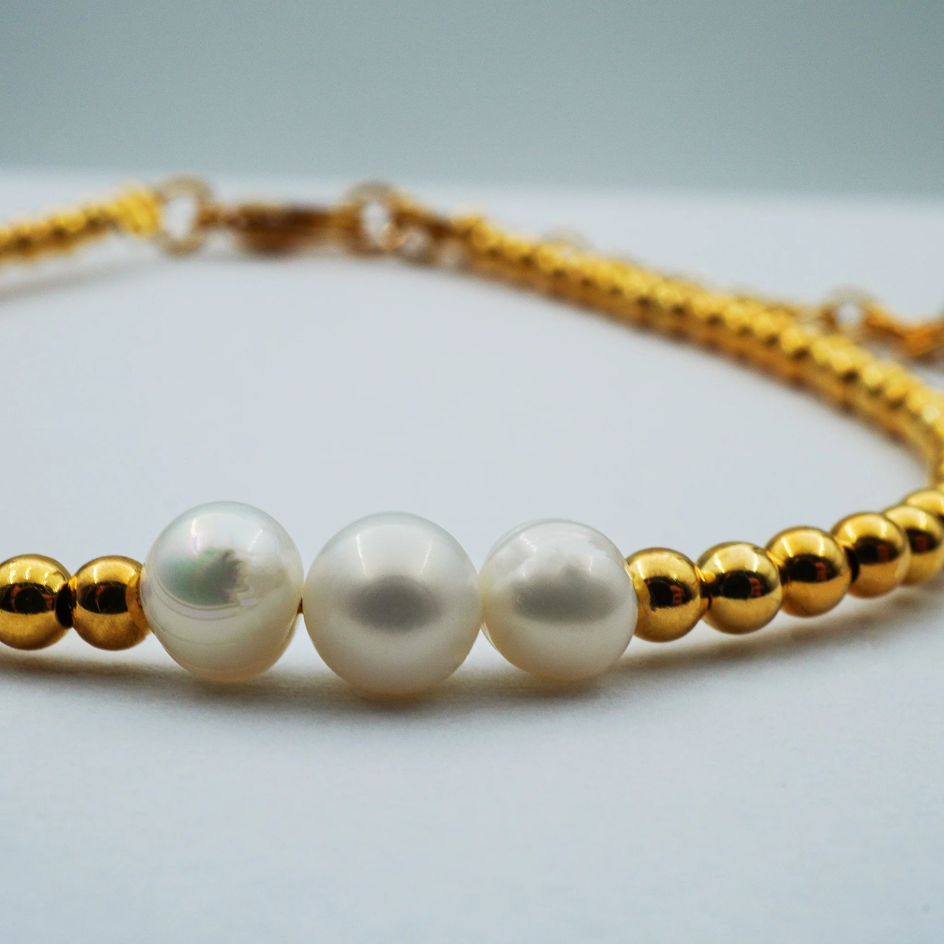 Close-up of the Golden Grace Pearl Bracelet highlighting smooth lustrous pearls paired with golden accents. Handmade in Bali, showcasing refined minimalist elegance with artisanal detail.