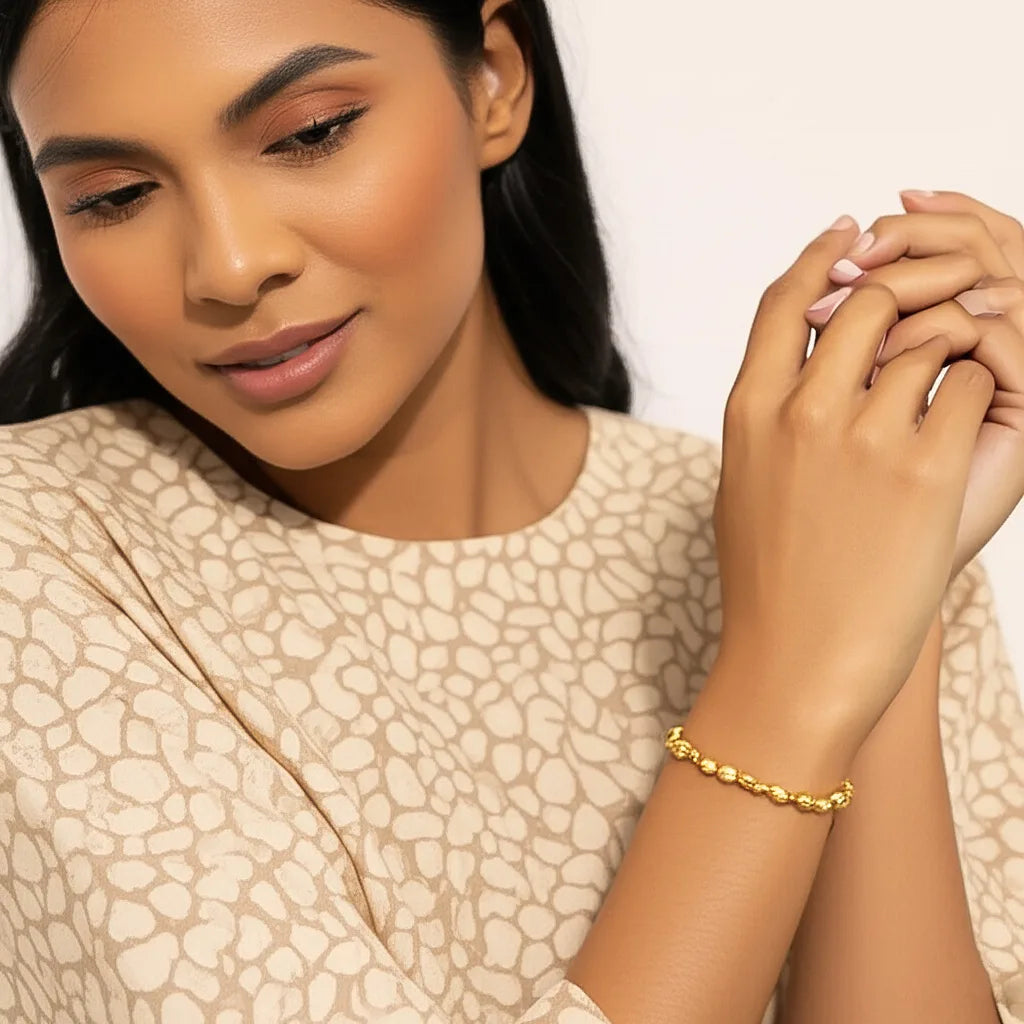 Model wearing the Golden Nugget Stretch Bracelet, showcasing sculpted gold beads in a radiant, minimalist Bali-inspired lifestyle setting.