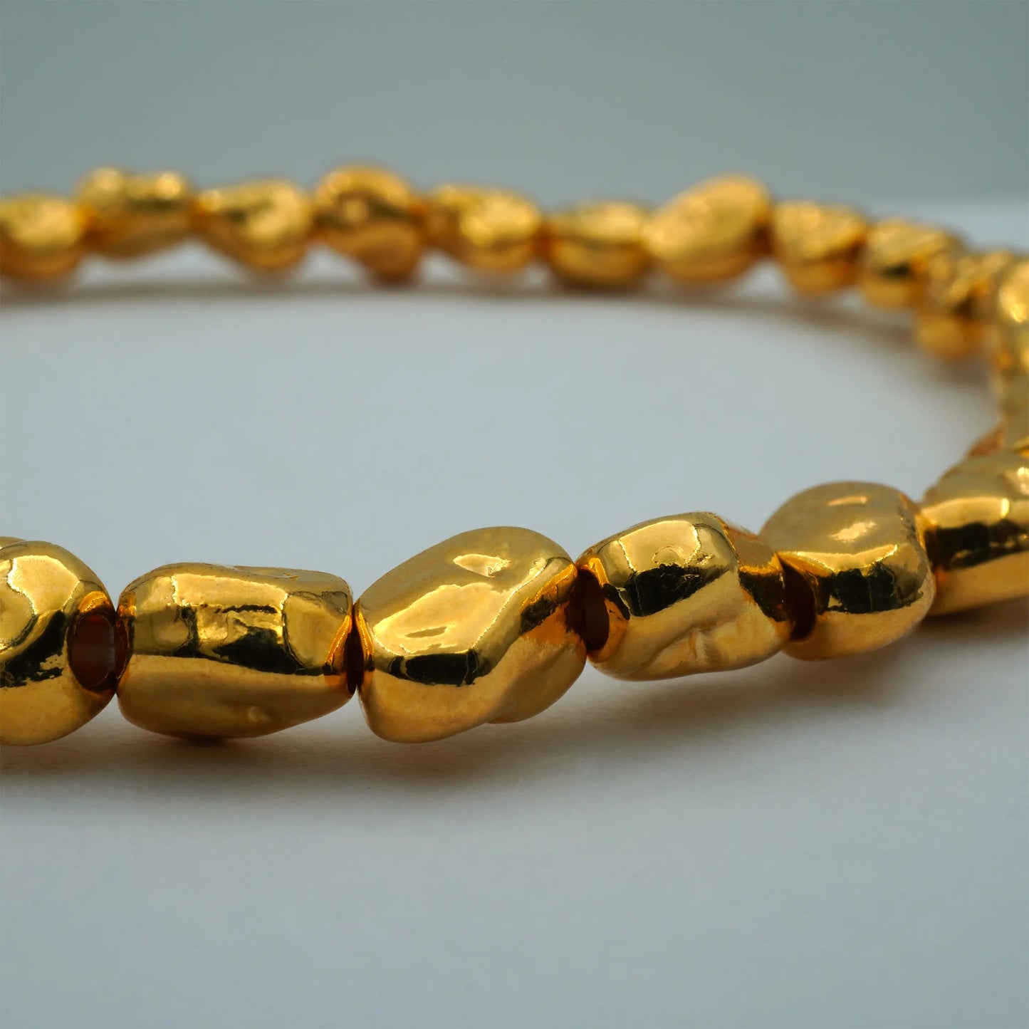 Close-up of the Golden Nugget Stretch Bracelet, highlighting the intricate detail and warm sheen of its organically shaped gold-toned beads.

