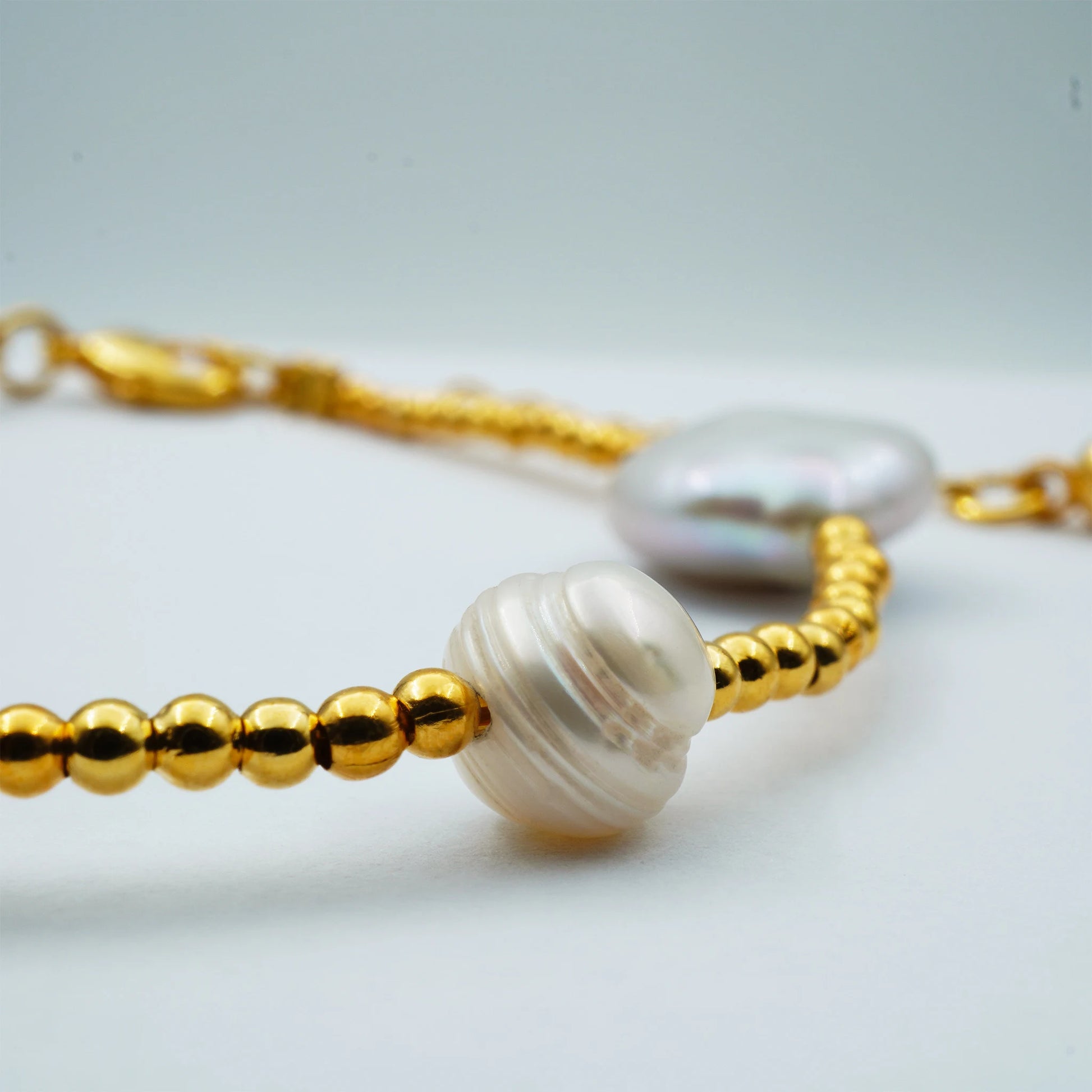 Close-up of the Golden Radiance Pearl Bracelet highlighting the luminous sheen of pearls contrasted with golden bead accents. Handmade in Bali, showcasing artisanal detail and boho elegance.