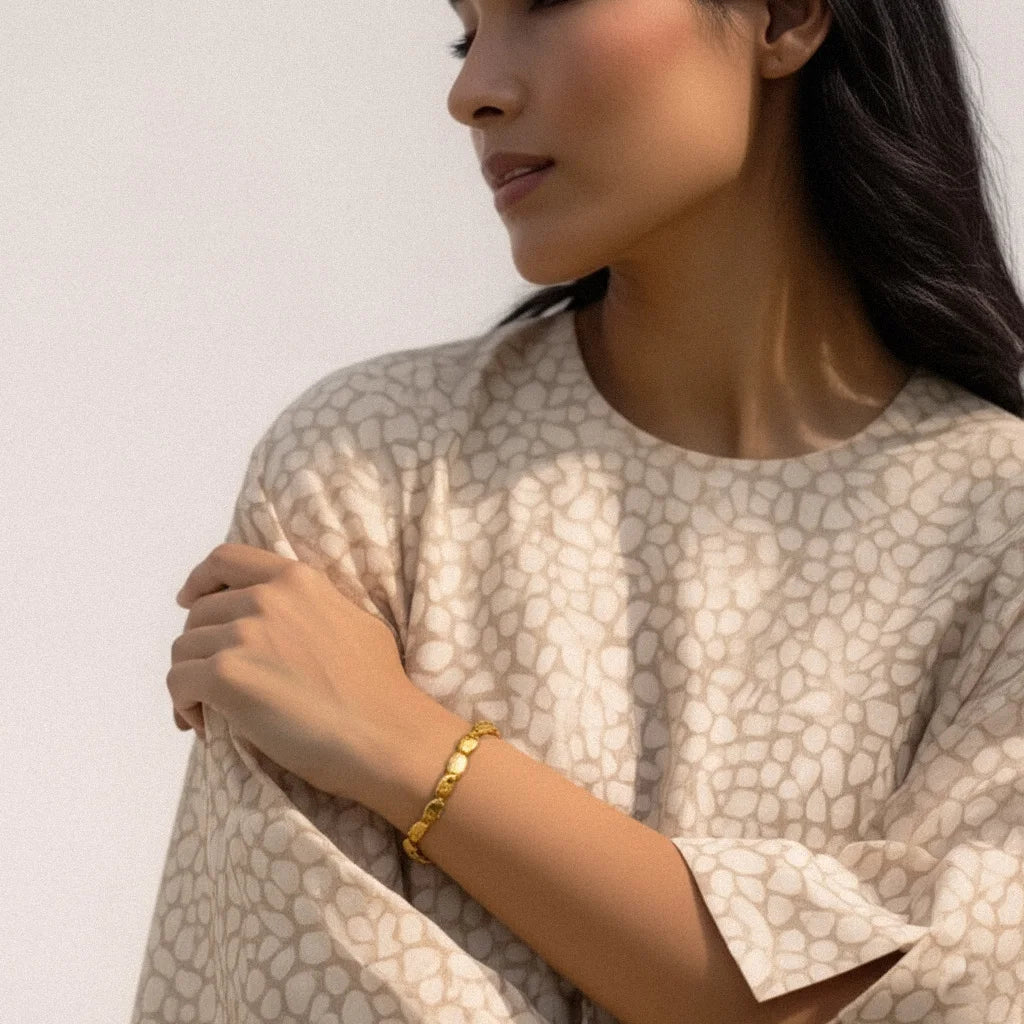 Model wearing the Golden Ripple Stretch Bracelet featuring sculptural gold-plated beads, styled in a warm, handmade Bali-inspired fashion scene.