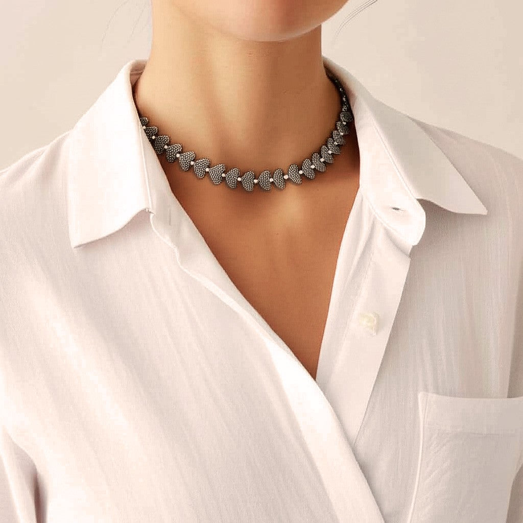 Woman wearing the Silver Heartbeat Sliding Necklace with silver-plated heart beads, styled with a white shirt in natural sunlight, handmade in Bali.