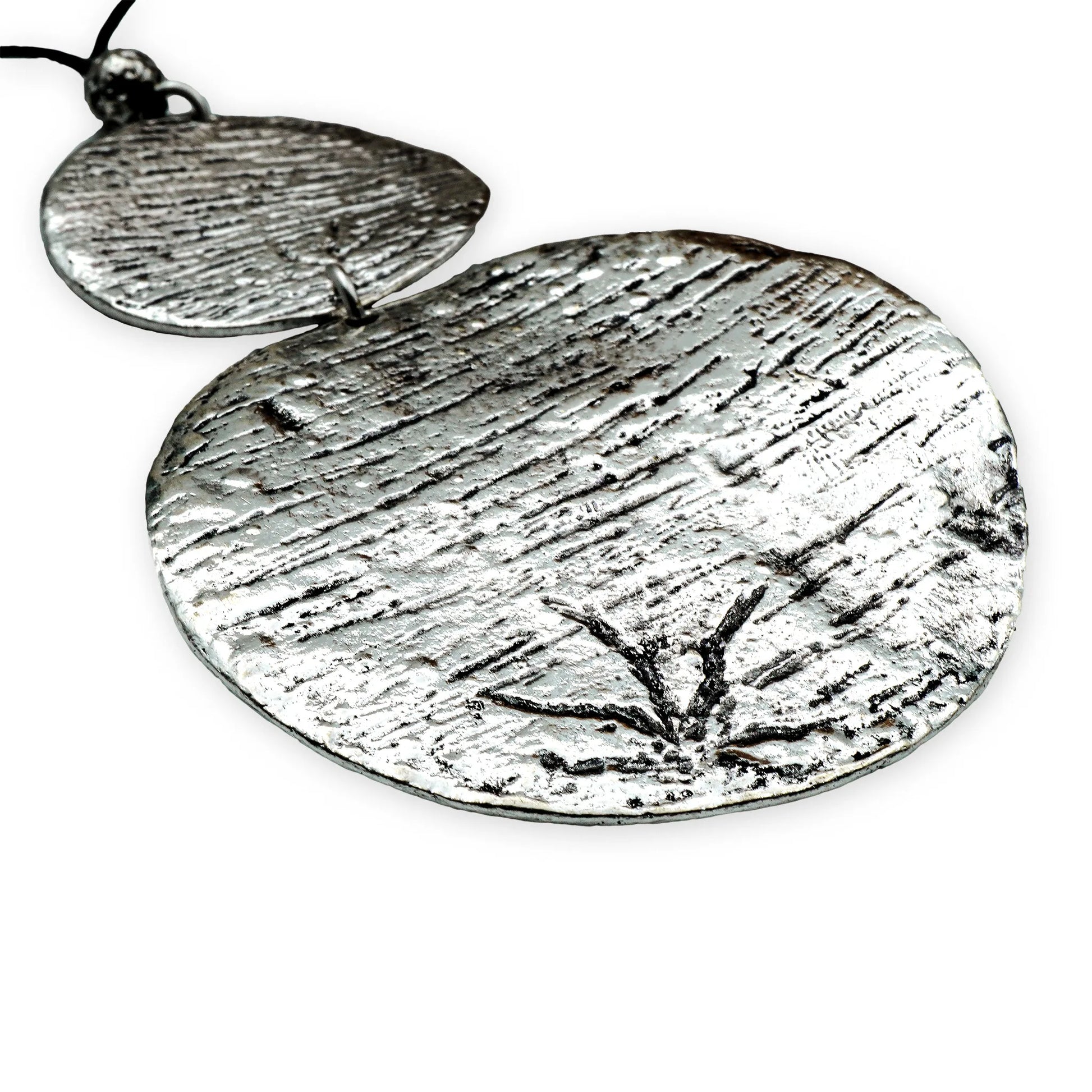 Close-up of the Lunar Balance Sliding Necklace by Camins Fashion, highlighting the hammered texture of the two silver medallions and the smooth black silk cord — a minimalist boho piece inspired by lunar phases.