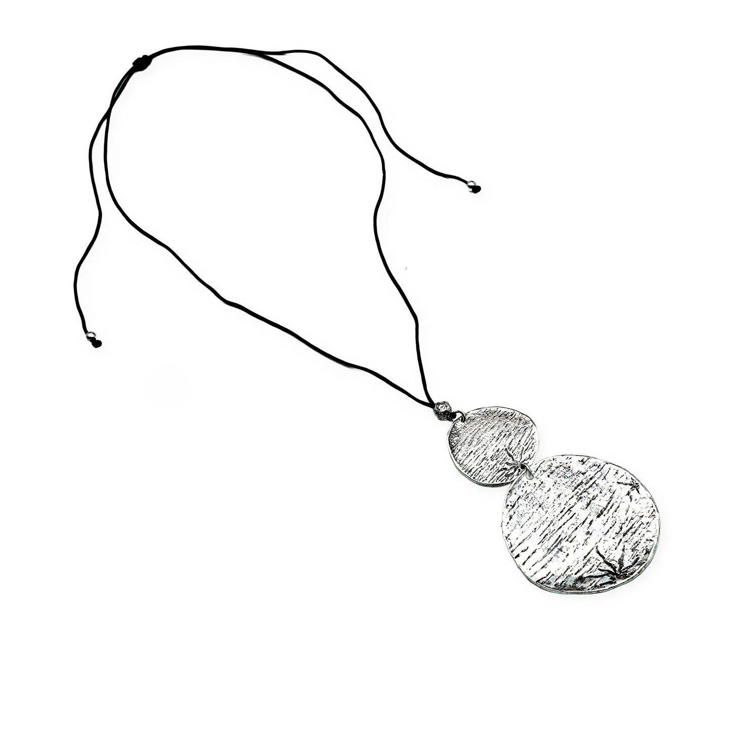 Top view of the Lunar Balance Sliding Necklace by Camins Fashion, showcasing two textured silver medallions connected on a smooth black silk cord — a handcrafted piece reflecting minimalist lunar symbolism and boho charm.