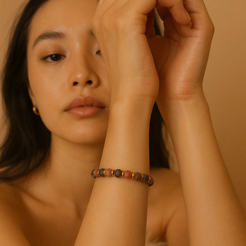 Woman wearing a rhodonite beaded bracelet with gold accents, captured in soft golden light, embodying Mediterranean-Boho elegance.