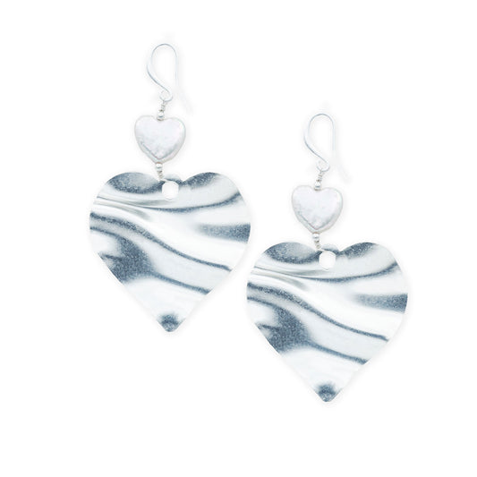 Top view of silver heart-shaped pearl earrings featuring a bold romantic design with a glossy finish, showcasing a two-heart structure for a modern, sculptural twist. A statement jewelry piece blending elegance and Mediterranean charm.