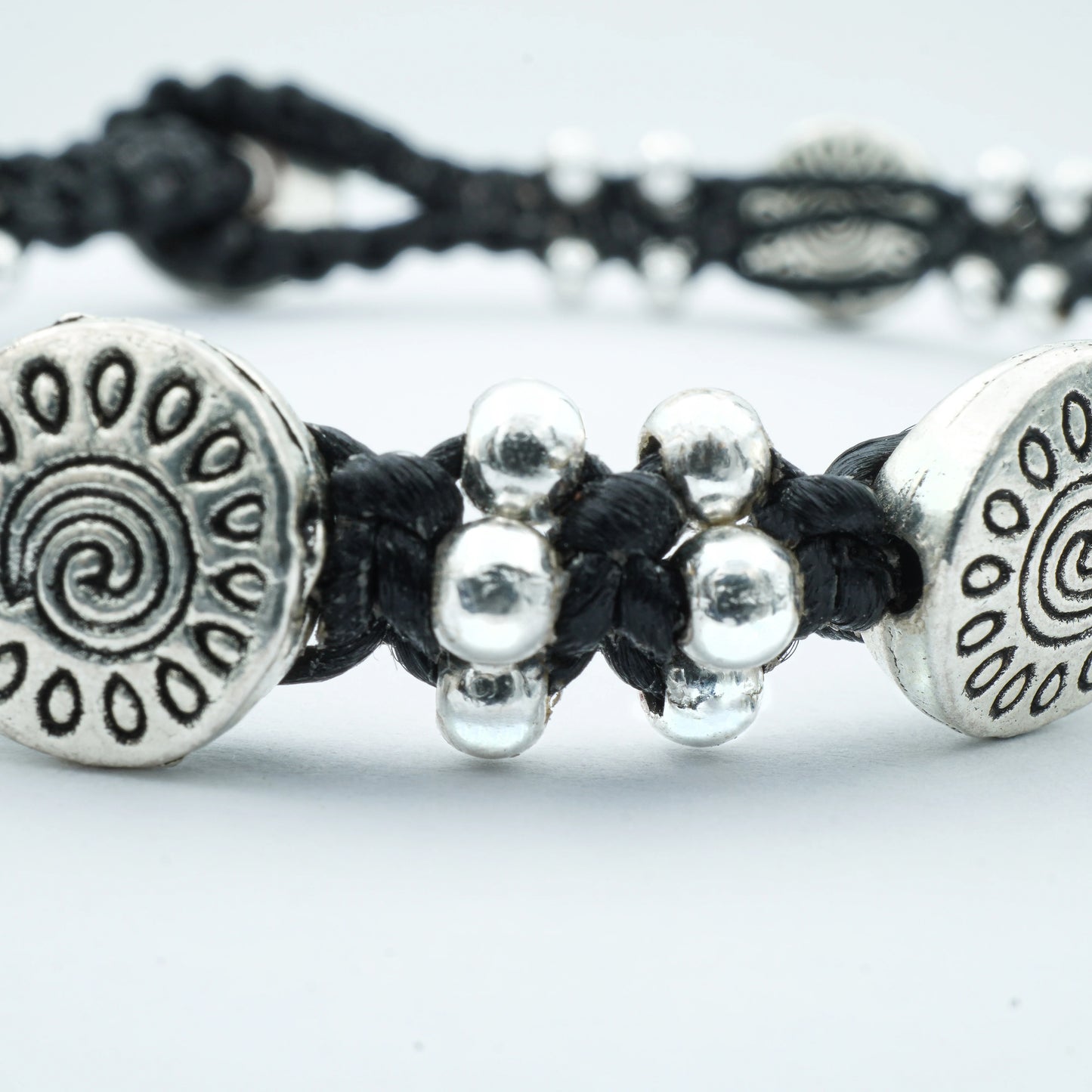 Close-up of the Sunburst Charm Bracelet by Camins Fashion, featuring silver sunburst charms and polished beads on a dark waxed cord — handcrafted in Bali with radiant boho style
