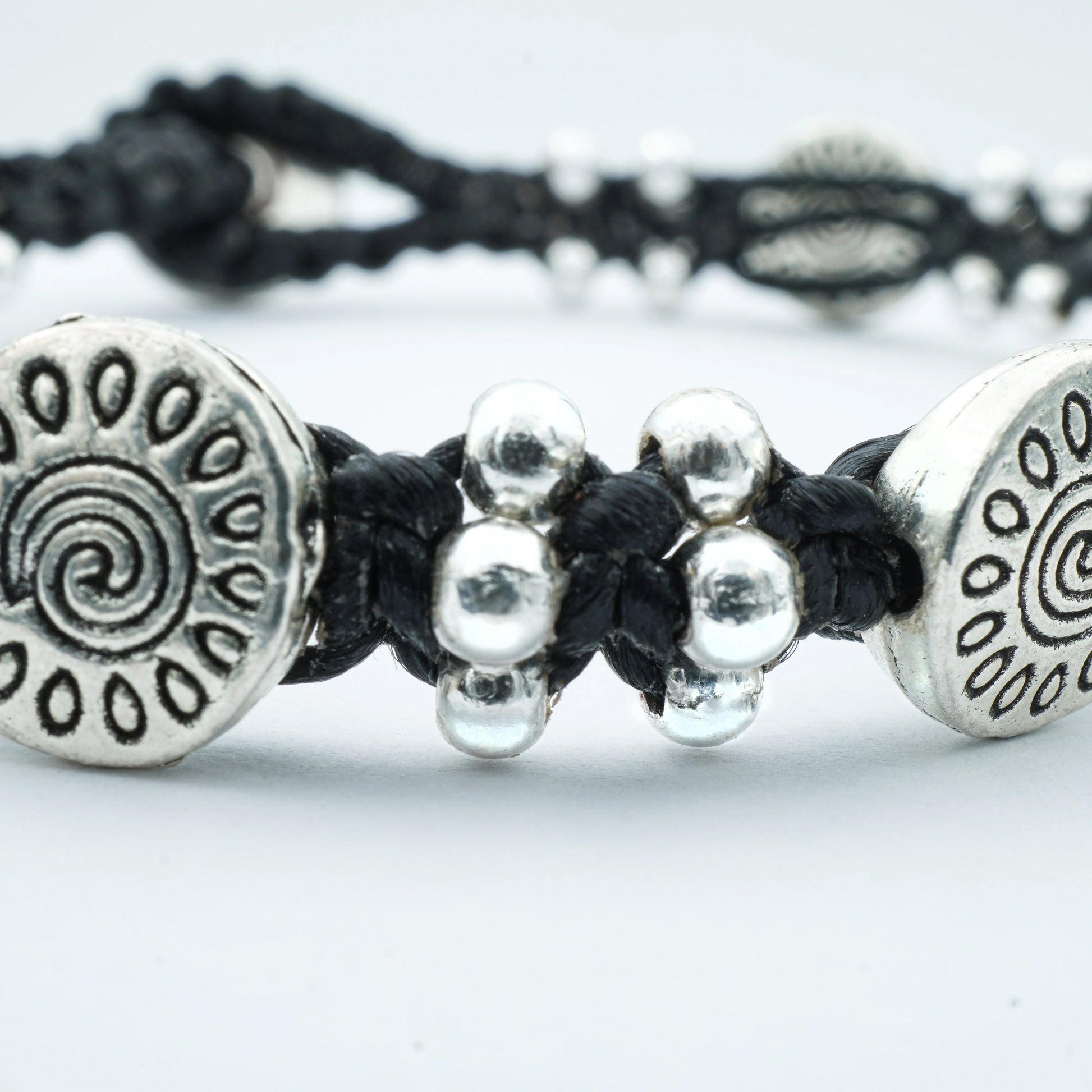 Close-up of the Sunburst Charm Bracelet by Camins Fashion, featuring silver sunburst charms and polished beads on a dark waxed cord — handcrafted in Bali with radiant boho style